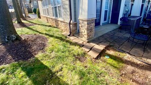 A residential house with a stone foundation, a covered porch, and a patio area with outdoor furniture. - Reedy River Retreat - Walk to Everything Downtown (Greenville)