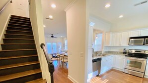 A modern kitchen with white cabinets, stainless steel appliances, and hardwood flooring. - Reedy River Retreat - Walk to Everything Downtown (Greenville)
