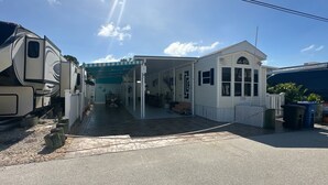 A small, single-story house with a covered porch and a fenced yard. - Cozy Trailer Retreat - Key Largo (key largo)