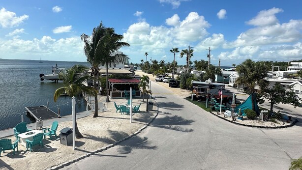A beachfront area with a sandy walkway, palm trees, and a view of the ocean. - Cozy Trailer Retreat - Key Largo (key largo)