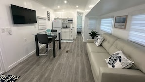 A compact living space with a kitchenette, dining area, and a sofa with decorative pillows. - Cozy Trailer Retreat - Key Largo (key largo)