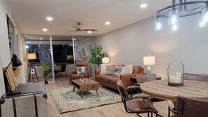 A spacious living room with a brown leather sofa, a wooden coffee table, and a dining area with a round table and chairs. - New Listing with Premier Host Luxury Meets Comfort Walk to Old Town Heated Pool (SCOTTSDALE)