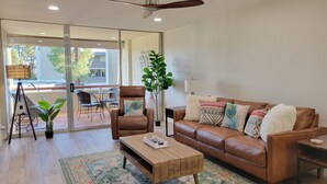 A modern living room with a brown leather sofa, a wooden coffee table, and a ceiling fan. - New Listing with Premier Host Luxury Meets Comfort Walk to Old Town Heated Pool (SCOTTSDALE)