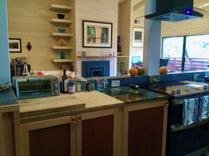 A kitchen with a microwave, toaster, and various kitchen items on the counter. There is a fireplace with a mantel and framed artwork above it. - Exclusive Mission Highlands 3-Bed Mid-Century Home – 5 Min to Sonoma Plaza (Sonoma)