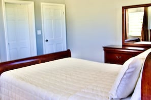 A bedroom with a bed, a dresser, and two doors.