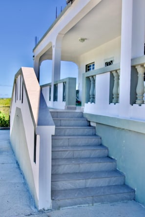 A staircase leading to a building with a white exterior and a balcony with balustrades.