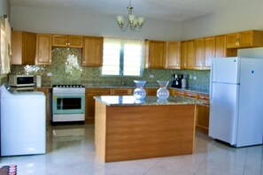 Una cocina con armarios de madera, una isla central, un refrigerador, un horno y un microondas.