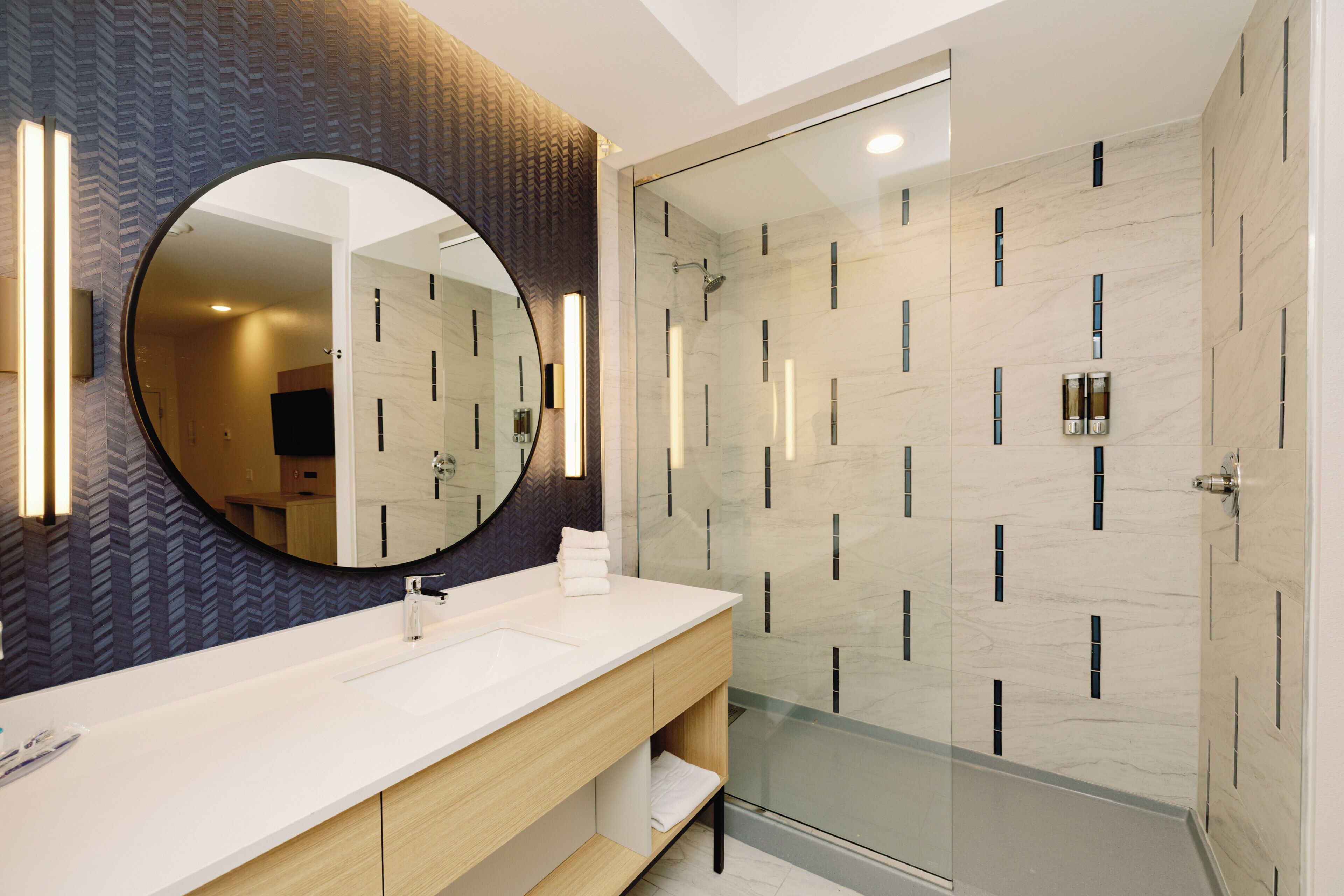 Une salle de bain moderne avec un grand miroir, une douche à parois de verre et un meuble-lavabo.