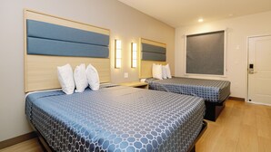 A hotel room with two beds, each with a headboard, a bedside table, and a wall-mounted light fixture. - Palace Inn Blue 290 W 43rd & Bingle Rd (Houston)