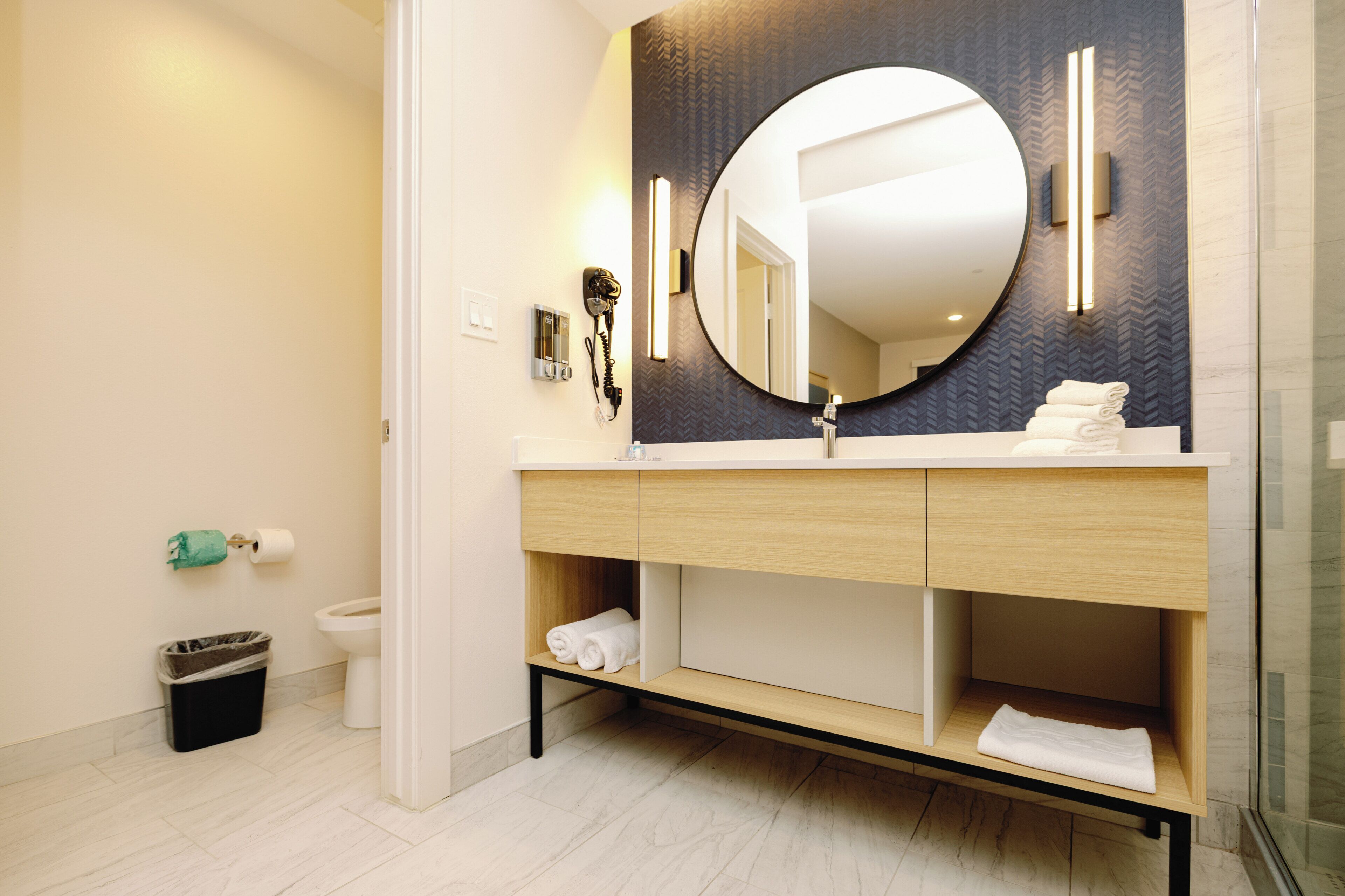 Un baño moderno con un espejo grande, un tocador con lavamanos y un inodoro.
