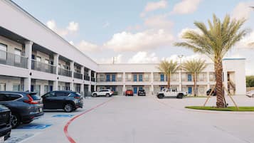 A multi-story parking garage with several cars parked, a clear sky, and a palm tree.