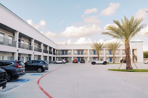A multi-story parking garage with several cars parked, a clear sky, and a palm tree.