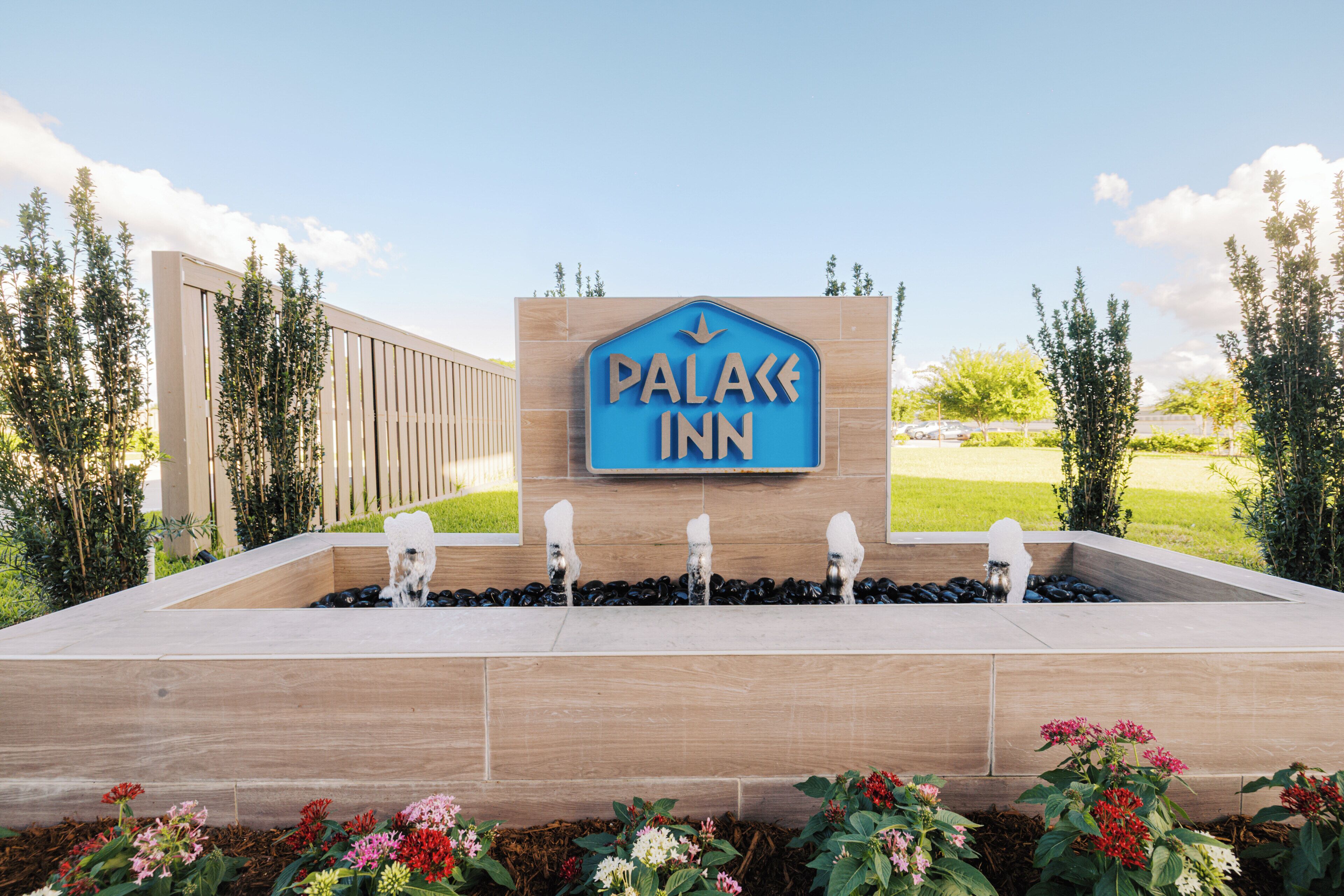 A sign for a hotel named 'Palace Inn' with a water feature in front.