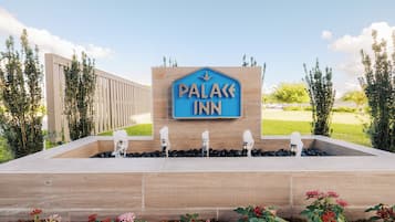 A sign for a hotel named 'Palace Inn' with a water feature in front.