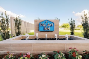 A sign for a hotel named 'Palace Inn' with a water feature in front. - Palace Inn Blue 290 W 43rd & Bingle Rd (Houston)