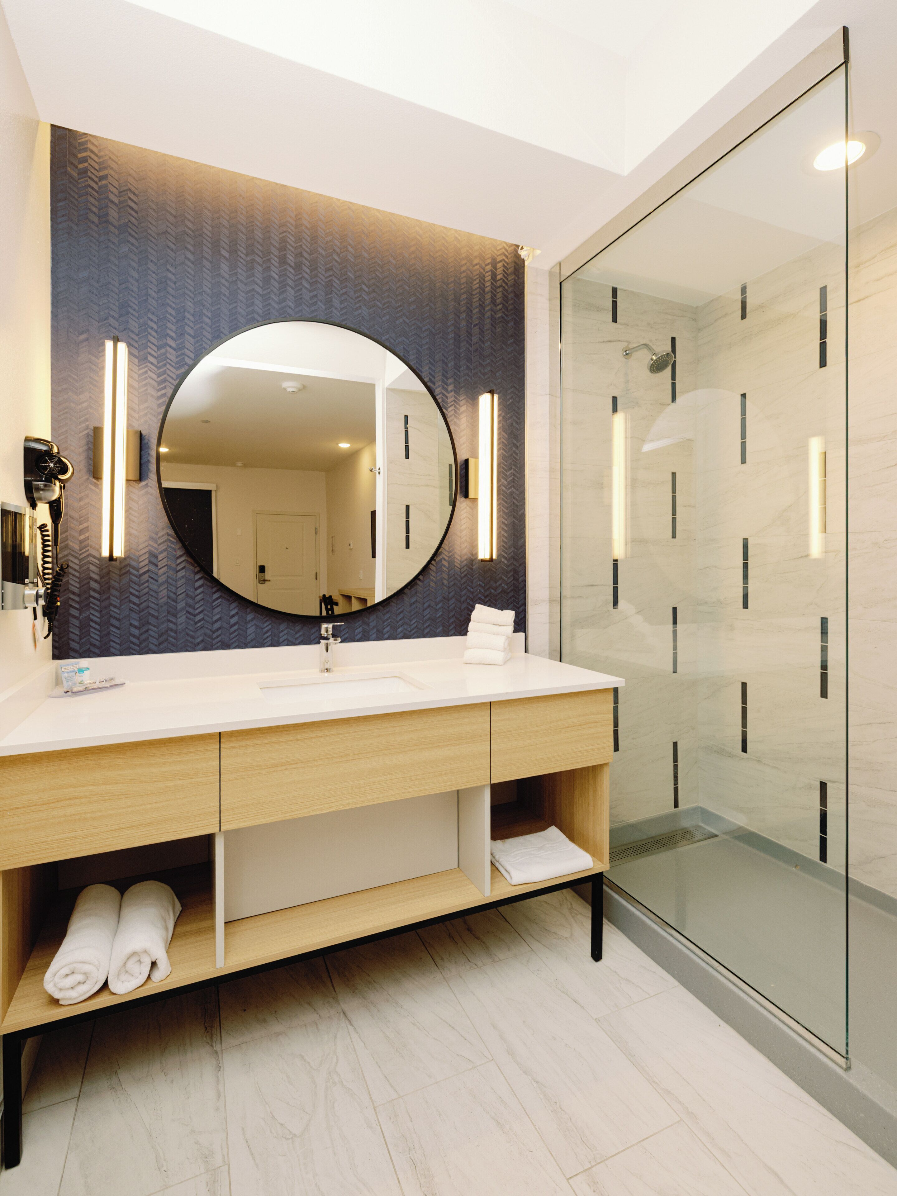 Un baño moderno con un espejo grande, un lavabo y una cabina de ducha de vidrio.