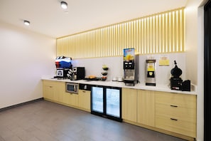 A modern kitchenette with a coffee machine, a mini-fridge, a microwave, and a beverage dispenser. - Palace Inn Blue 290 W 43rd & Bingle Rd (Houston)