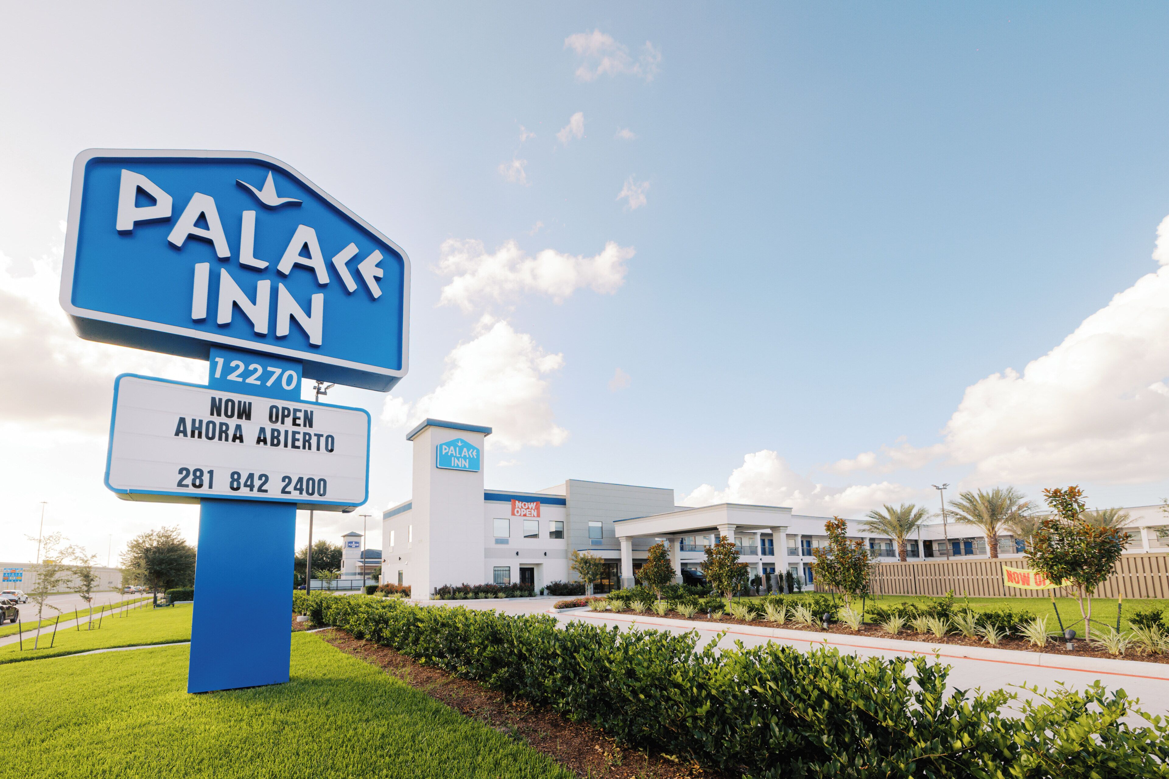 A sign for a hotel named 'Palace Inn' with a contact number and a note indicating it is now open.