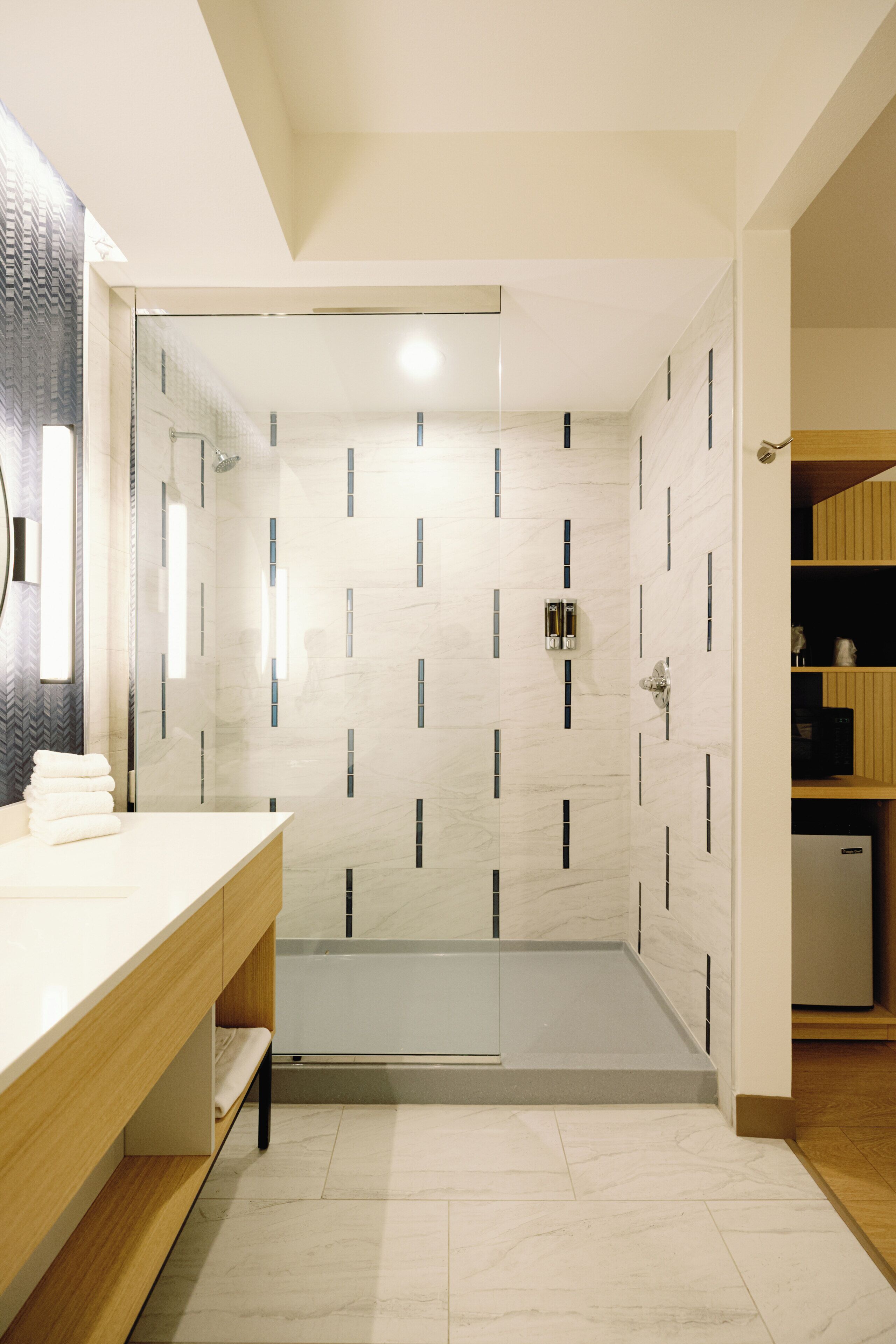 Un baño moderno con ducha, tocador y espejo.
