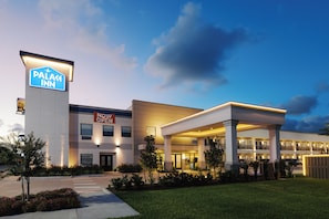 A hotel with a sign indicating it is now open, a covered entrance, and a landscaped front yard. - Palace Inn Blue 290 W 43rd & Bingle Rd (Houston)