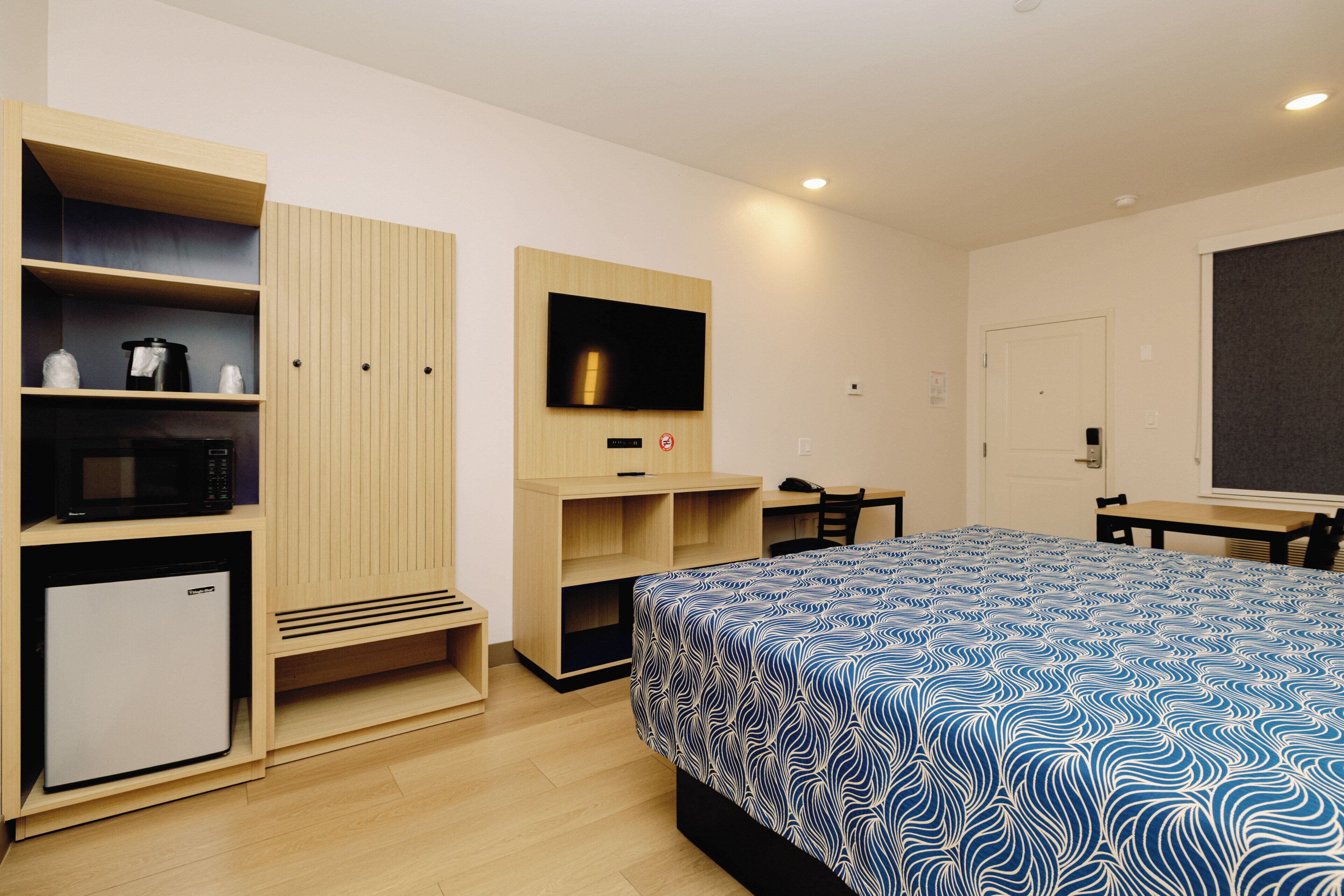A hotel room with a bed, a TV, a desk, and a wardrobe.