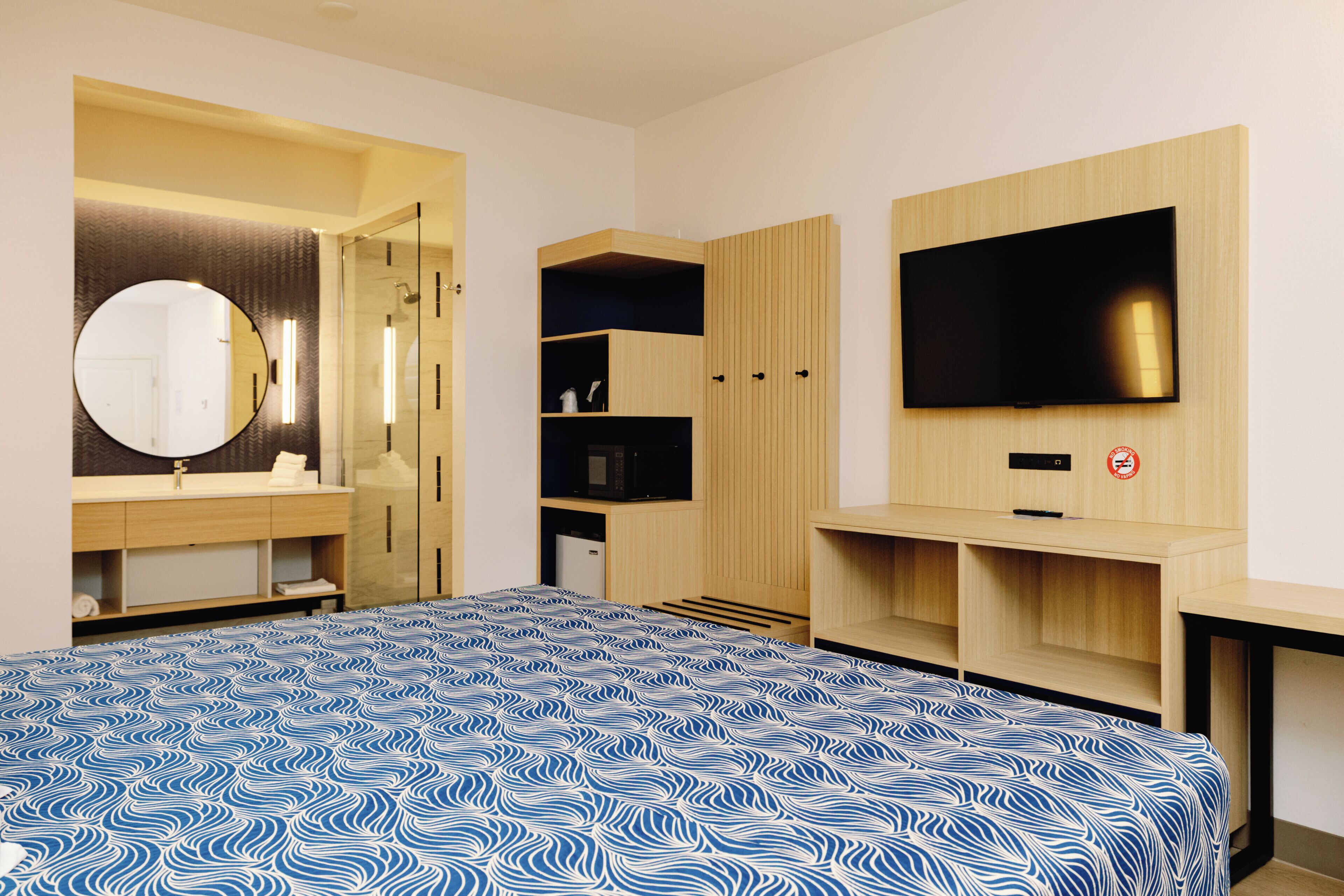 Een moderne slaapkamer met een groot bed, een inbouwkast, een spiegel en een flatscreen televisie.