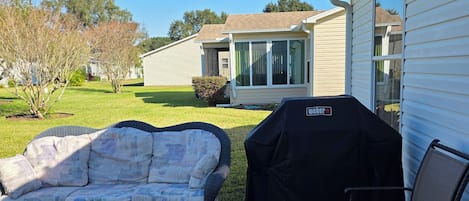 A patio with outdoor furniture, a grill, and a house in the background.
