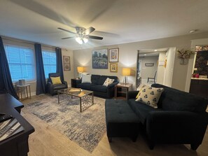 A living room with a ceiling fan, two couches, a coffee table, and a piano.