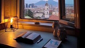 Una stanza con vista sulla città, una scrivania con una lampada e un quaderno.