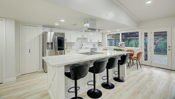 A modern kitchen with a central island, bar stools, and a dining area with a view of the garden. - Houston white house, private pool, patio and game room the best place in Houston (Houston)