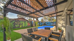 A covered patio with a pool, outdoor furniture, and a mural on the wall. - Houston white house, private pool, patio and game room the best place in Houston (Houston)