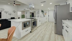 A modern kitchen with white cabinetry, stainless steel appliances, and a central island. - Houston white house, private pool, patio and game room the best place in Houston (Houston)