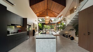 Una cocina moderna con una isla central, armarios oscuros y techo de madera.