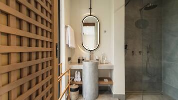 A modern bathroom with a freestanding mirror, a sink, a shower, and a wooden lattice partition.