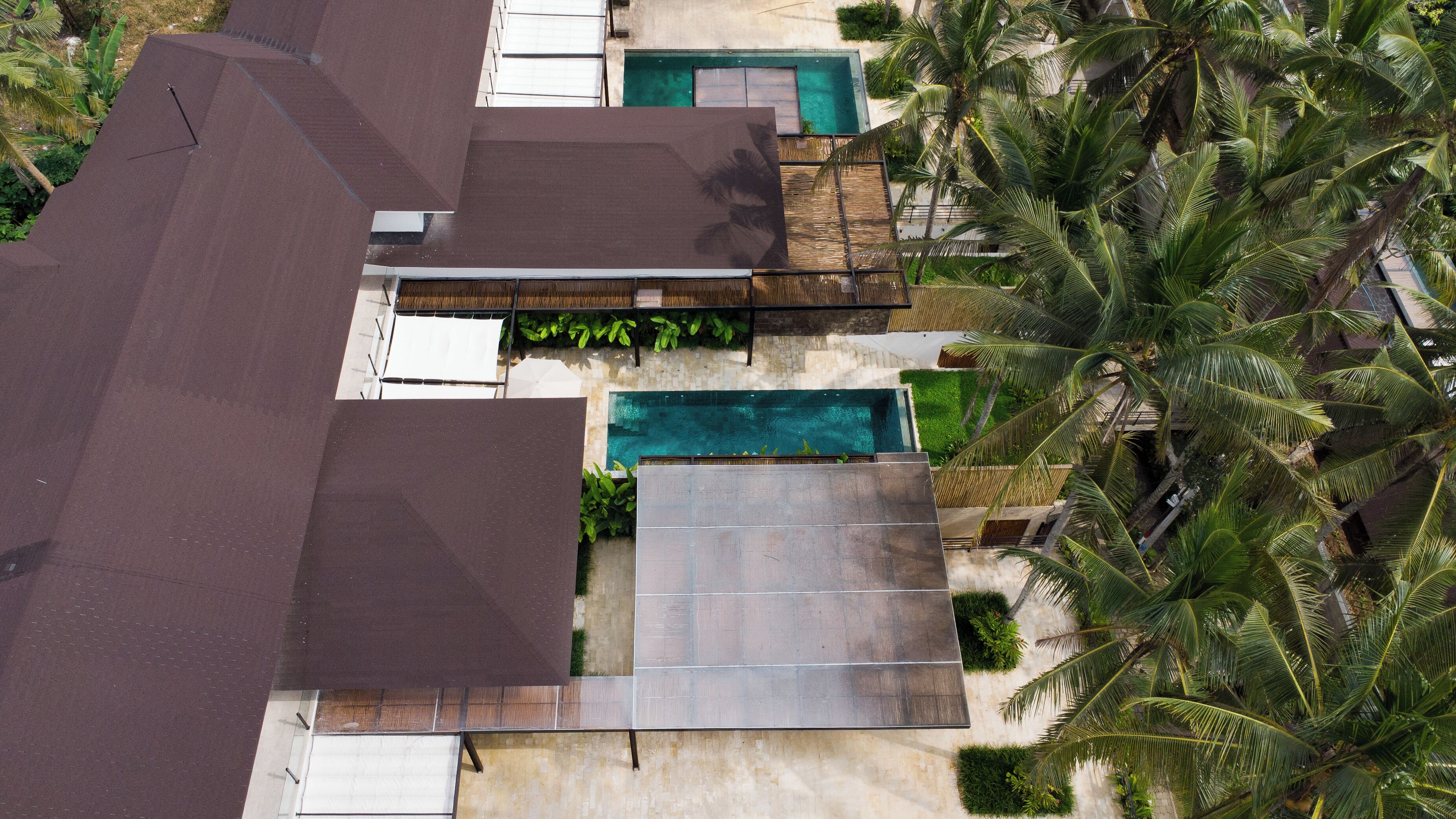 Una proprietà residenziale con piscina, patio coperto e palme circostanti.