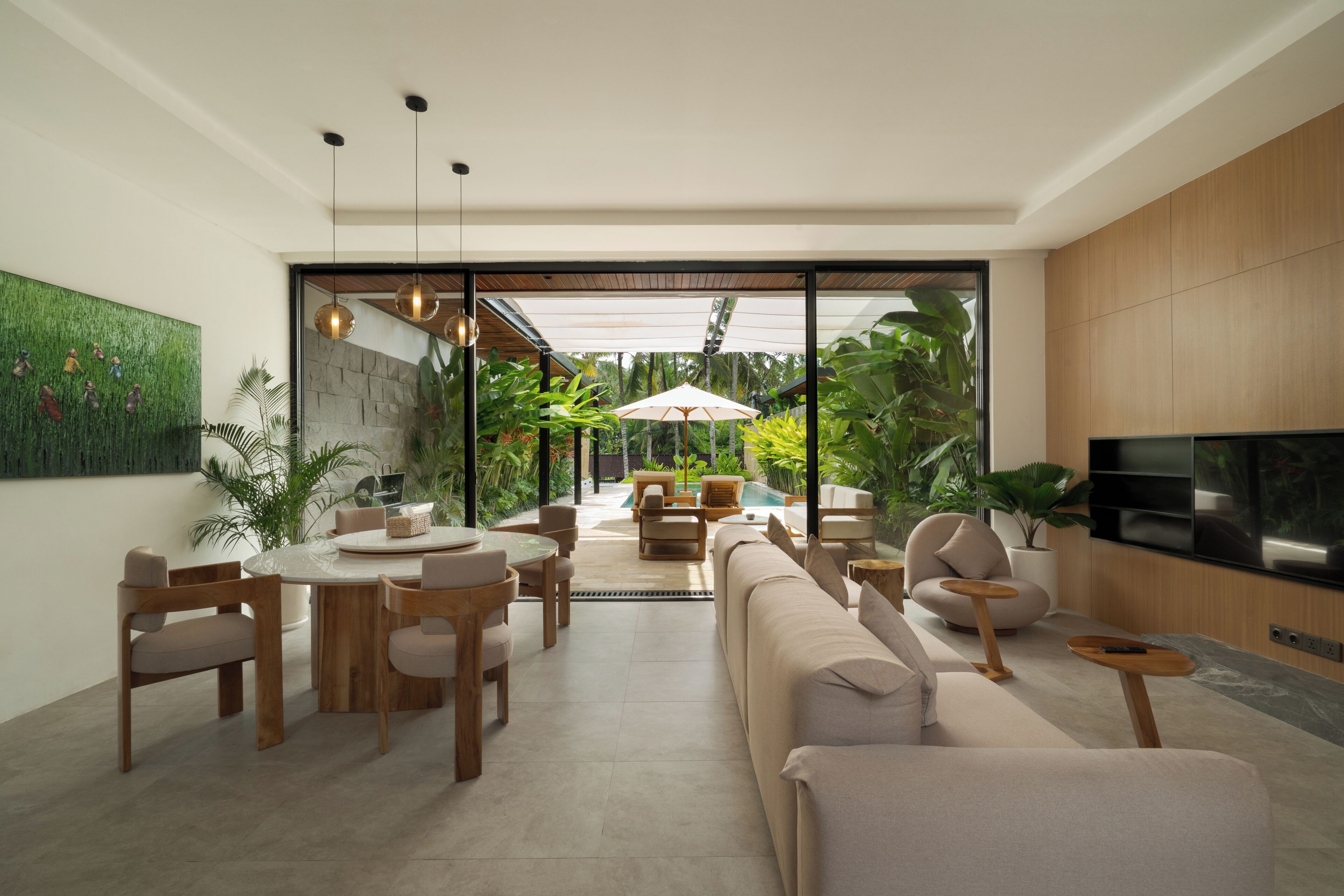 A modern living room with a dining area, a large TV, and a view of a pool and garden.