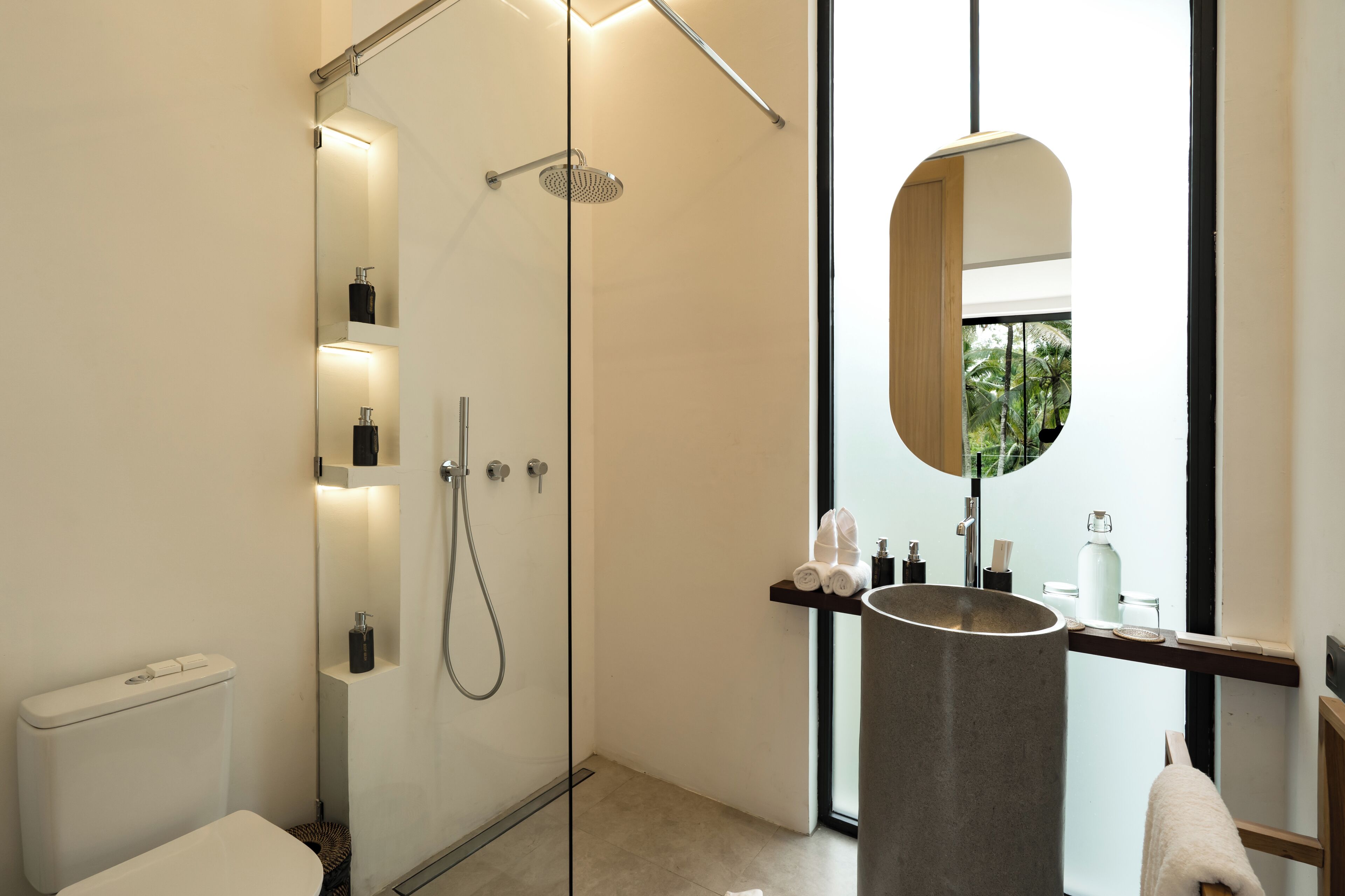 A modern bathroom with a glass-enclosed shower, a large mirror, and a built-in sink.