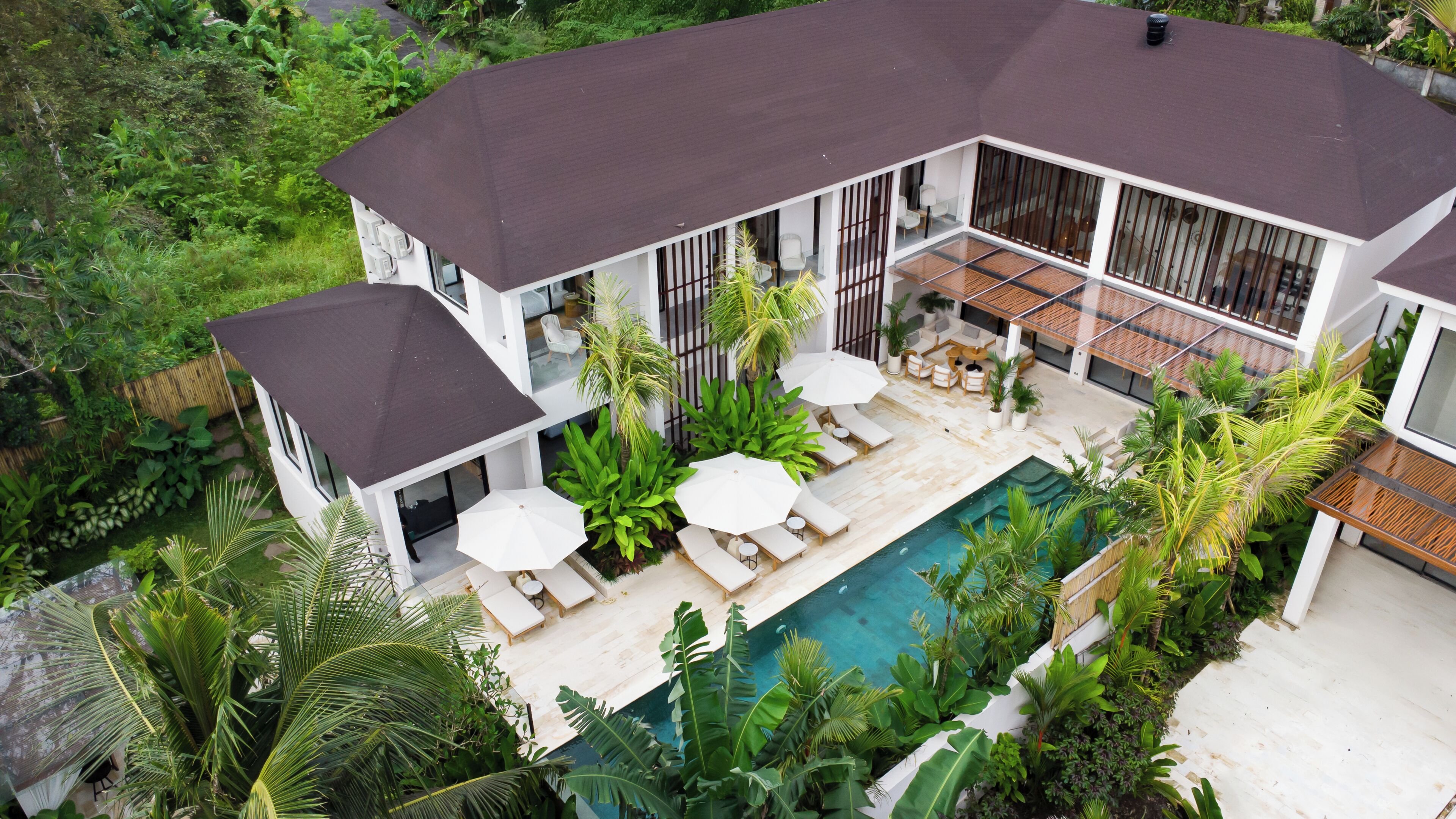A modern house with a swimming pool, outdoor seating, and lush greenery.