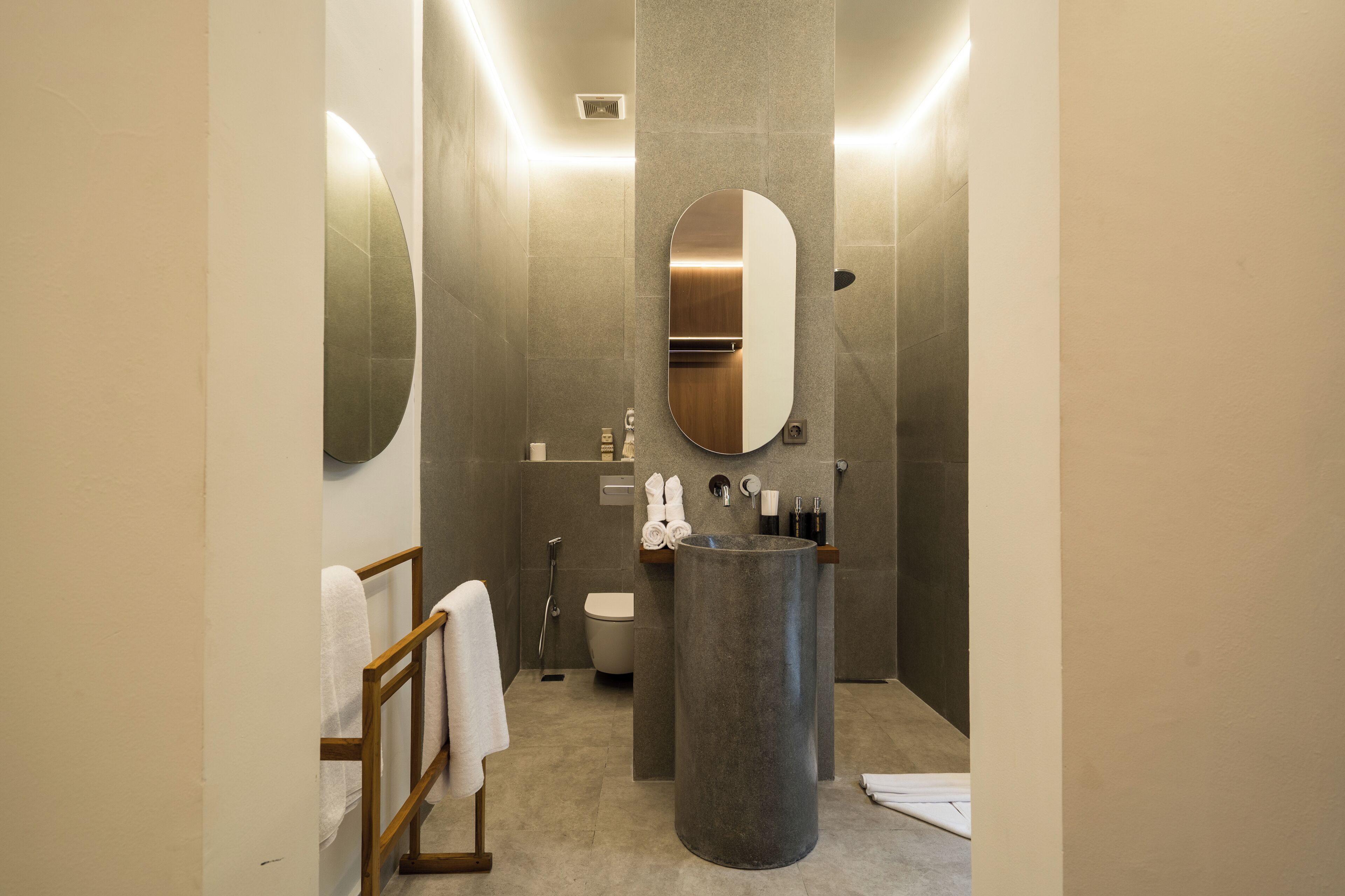 A modern bathroom with a round sink, a toilet, and a large mirror.