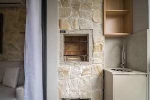A stone fireplace with a metal shelf, a wooden shelf above it, and a sink with a faucet. - Apt w/ BBQ & Balcony 220 m From the Beach Rty0216 (Florianópolis)