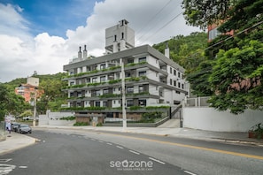 Un edificio de varios pisos con diseño moderno, con balcones adornados con plantas.