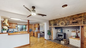 A spacious kitchen with wooden cabinets, a central island, and a stone fireplace. - Charming house w/ wifi, fireplace & dog-friendly (Shelton)