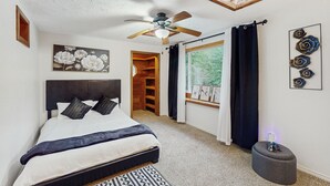 A bedroom with a bed, ceiling fan, wooden closet, window with curtains, and artwork on the wall. - Charming house w/ wifi, fireplace & dog-friendly (Shelton)