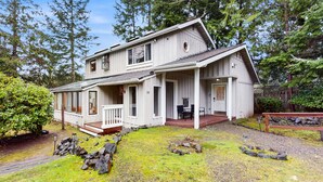 A two-story house with a porch, a covered front porch area, and a stone pathway leading to the entrance. - Charming house w/ wifi, fireplace & dog-friendly (Shelton)