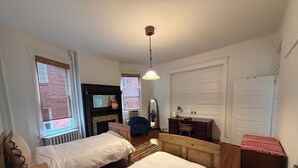 Une chambre avec deux lits, une commode, une chaise, un bureau et un miroir.