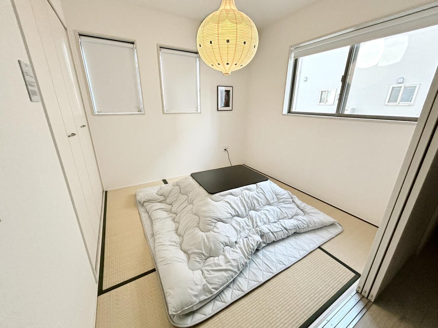 A small, neatly arranged bedroom with a bed, a small table, and a window.
