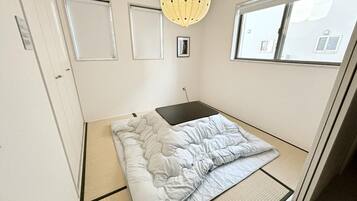 A small, neatly arranged bedroom with a bed, a small table, and a window.