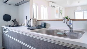 Una cocina moderna con un lavamanos de acero inoxidable, una tetera y una cafetera.