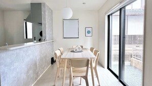 Una cucina moderna con una grande isola, una zona pranzo con tavolo e sedie in legno e un'ampia porta-finestra scorrevole che dà sull'esterno.
