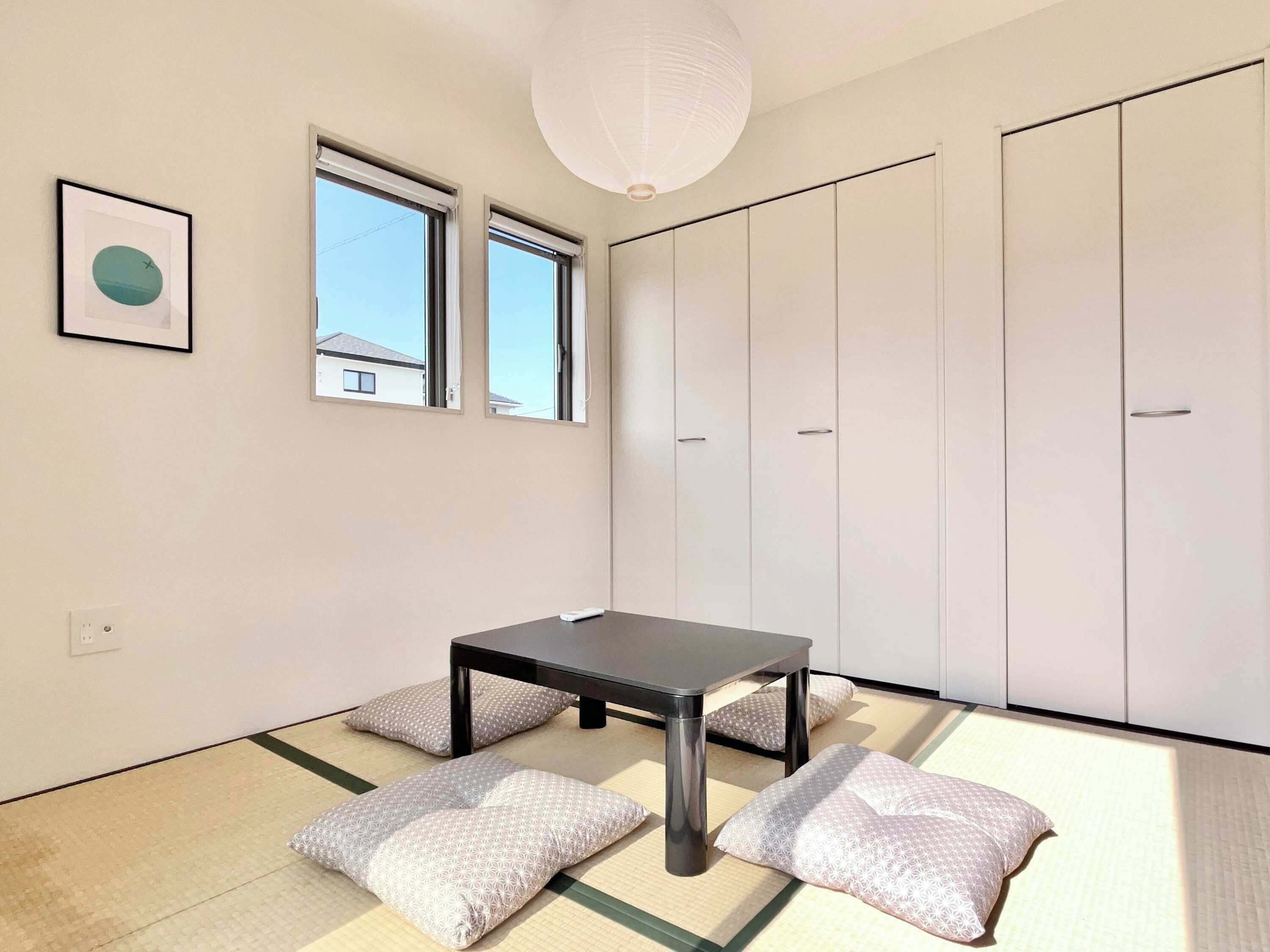 A minimalist room with tatami flooring, a low table, and a wardrobe.